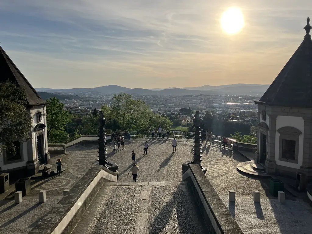 Atardecer desde el Santuario de Bom Jesus do Monte, con el sol bajo sobre el horizonte y la ciudad de Braga al fondo.