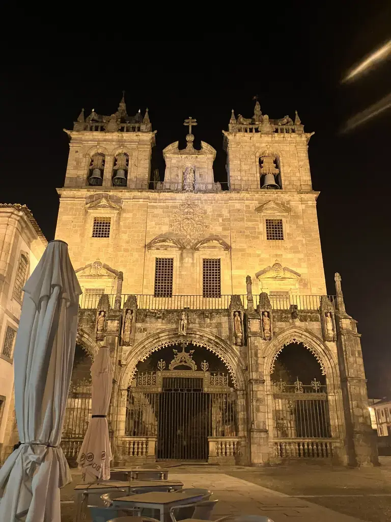 Fachada iluminada de la Sé de Braga (Catedral de Braga) durante la noche, con sus dos torres y detalles arquitectónicos góticos.